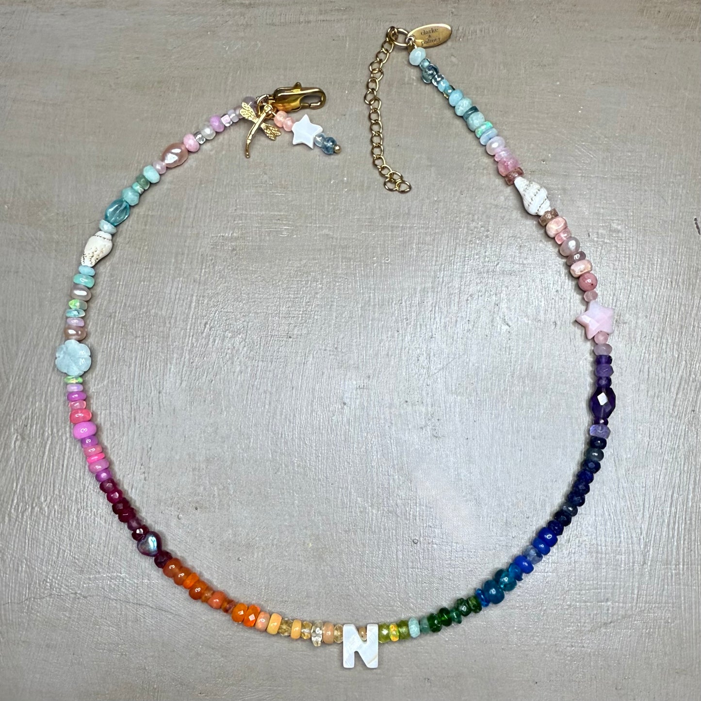 Multicolored gemstone beaded necklace with a letter 'N' charm on a neutral surface