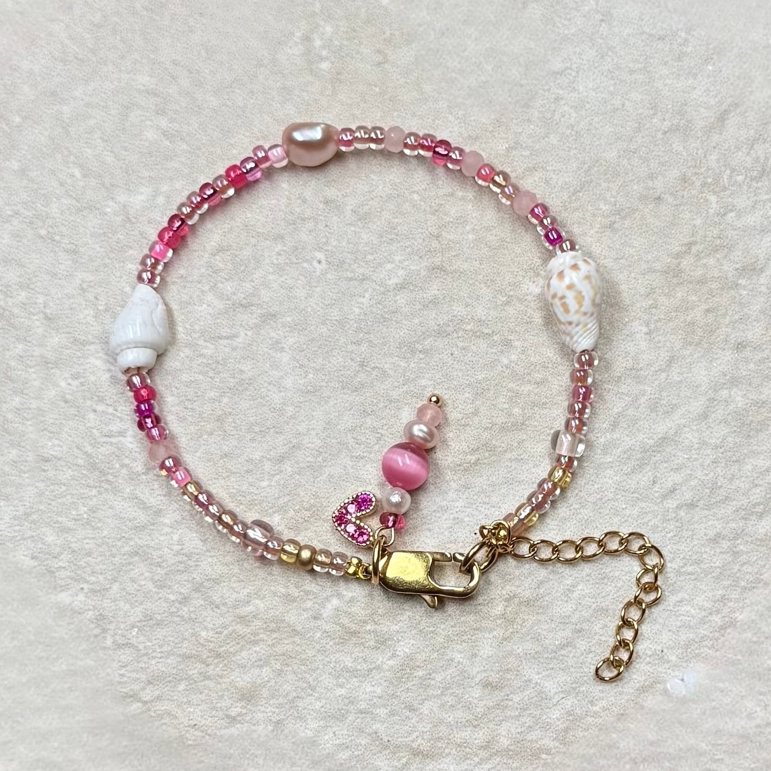 Beaded bracelet with shells, pink and white beads on a light gray background