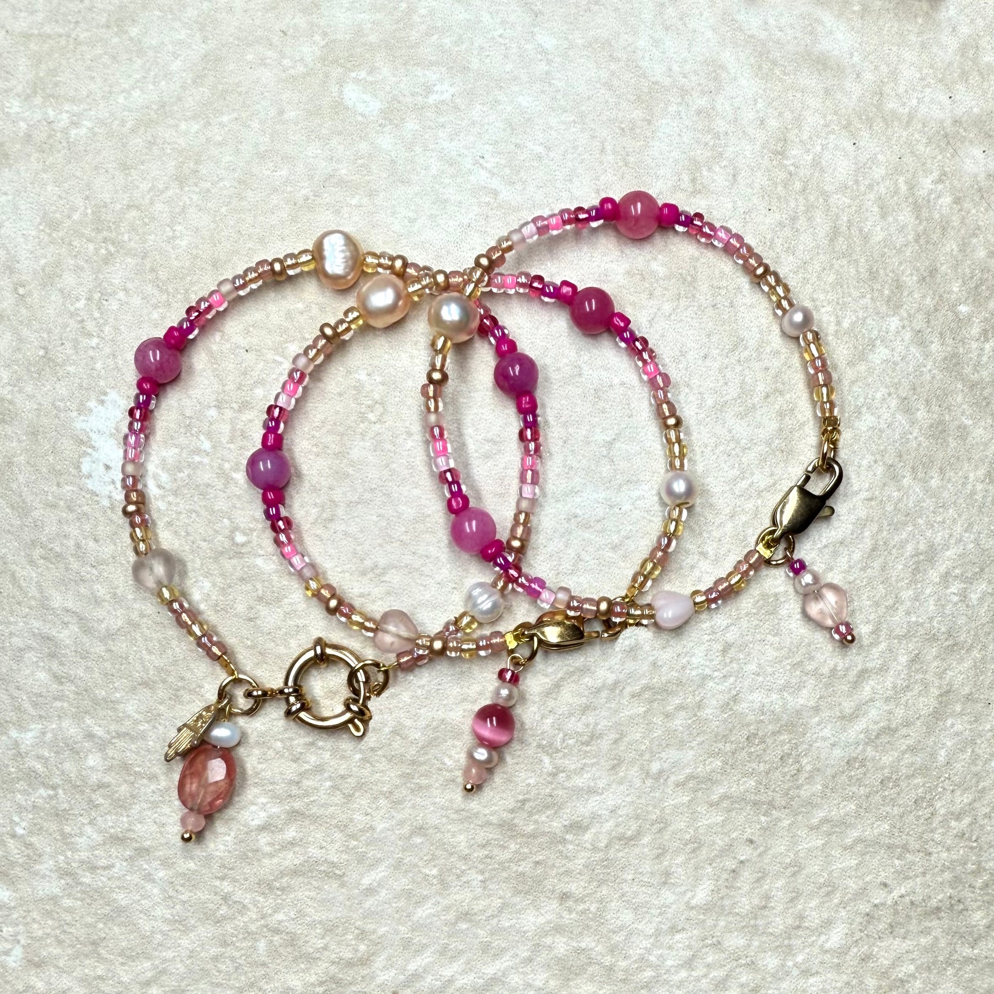 Set of pink beaded bracelets on a textured beige surface