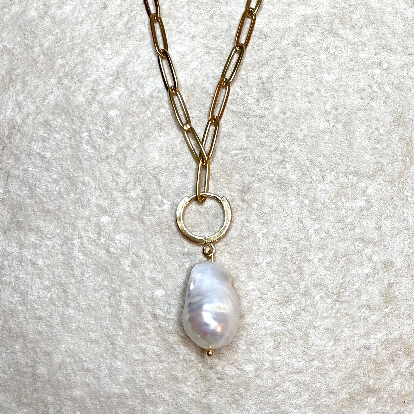 Necklace with a pearl pendant on a textured gray background