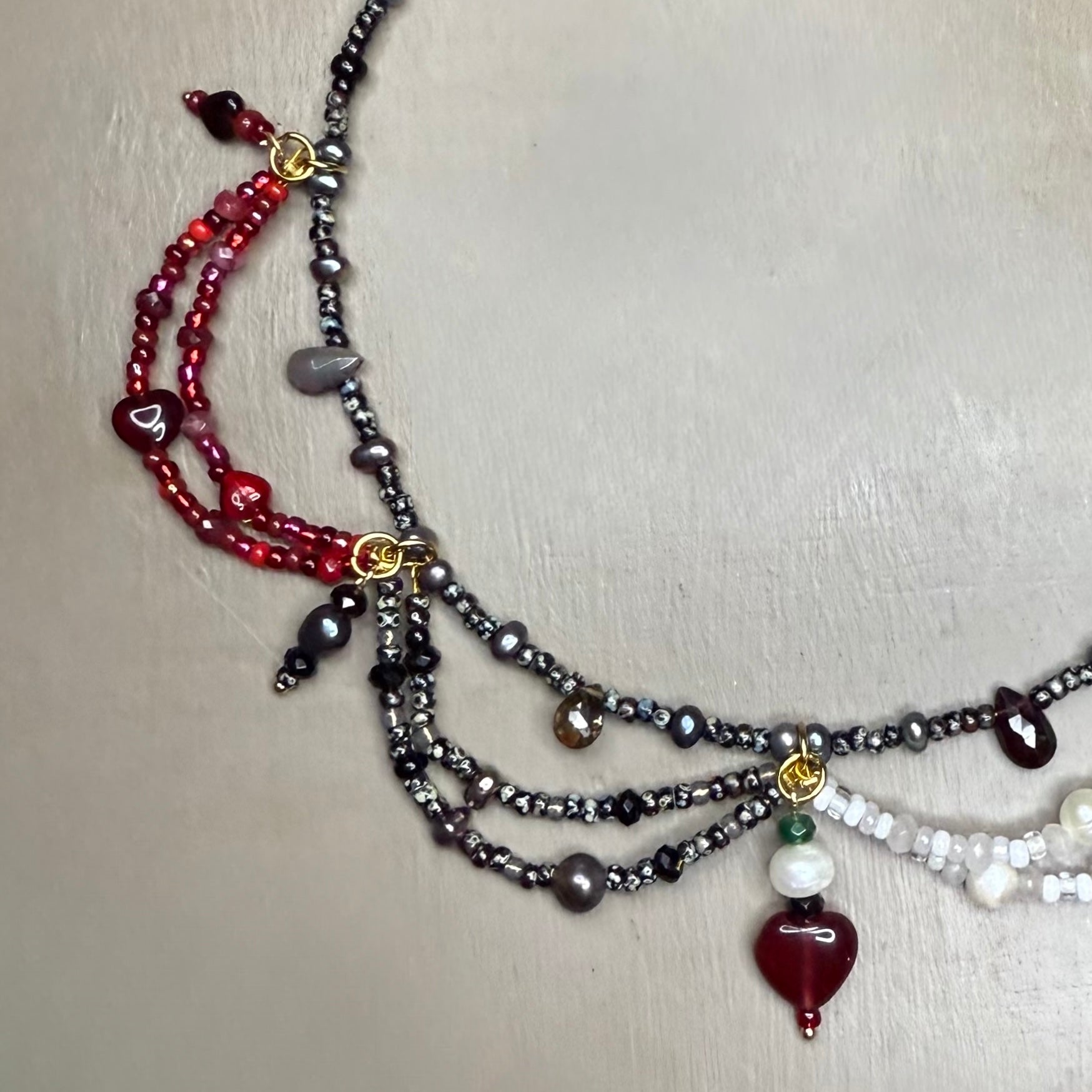 Multistrand beaded necklace with various gemstone colored beads on a light gray background