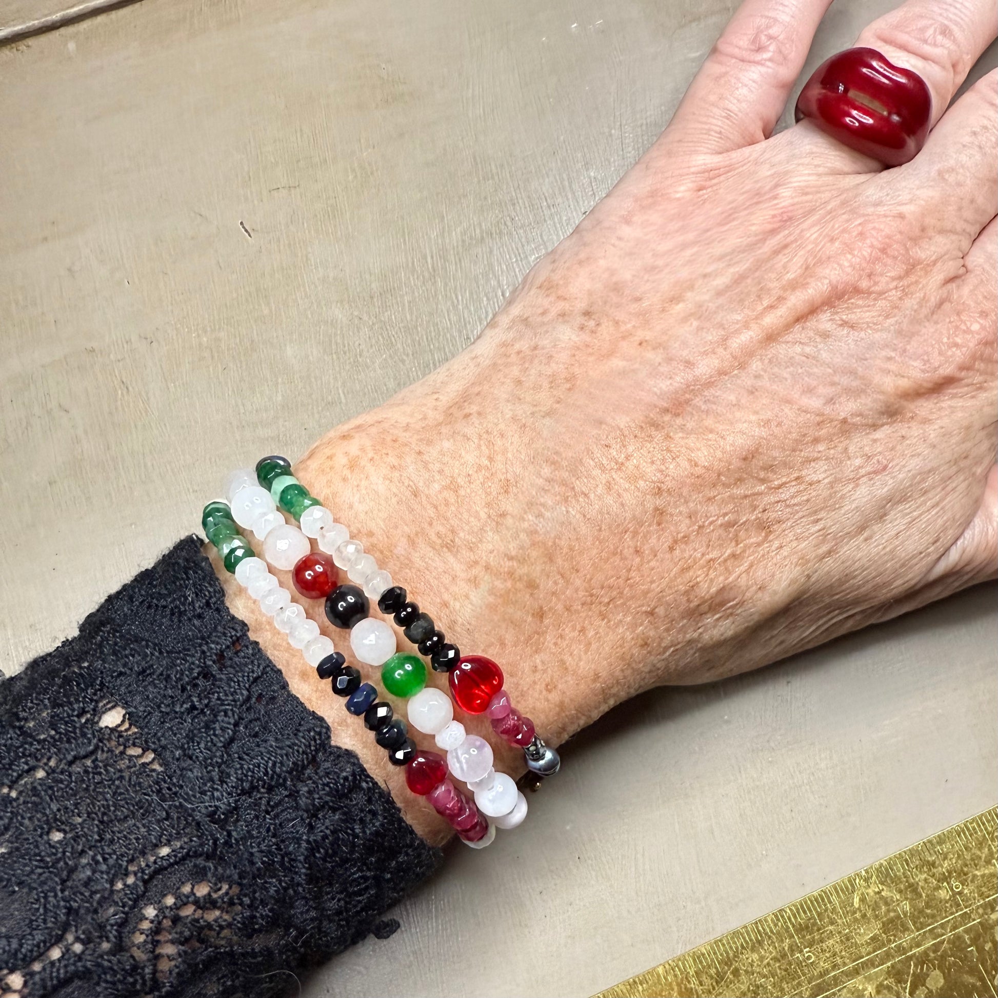 Close-up of a wrist wearing colorful gemstone beaded bracelets on a neutral background