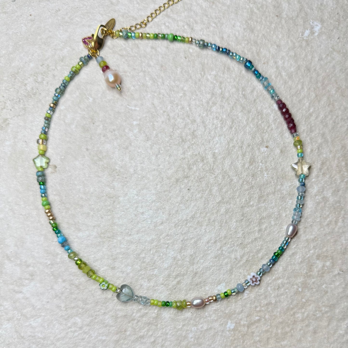 Beaded gemstone in aquamarine, aventurine and pearl necklace on a textured surface