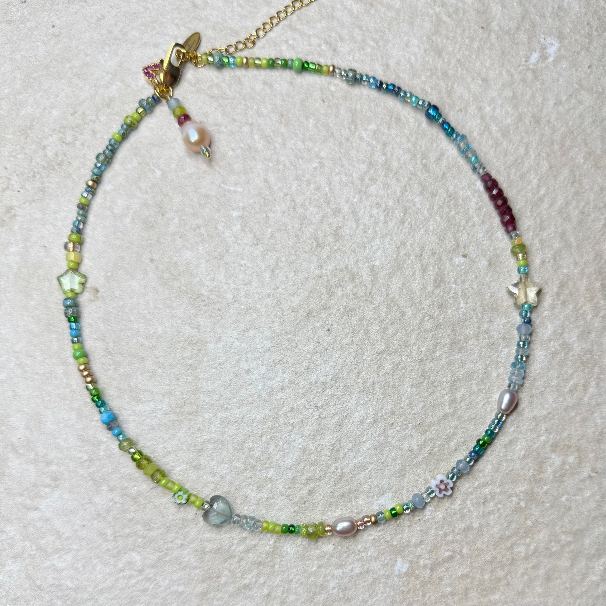 Beaded gemstone in aquamarine, aventurine and pearl necklace on a textured surface