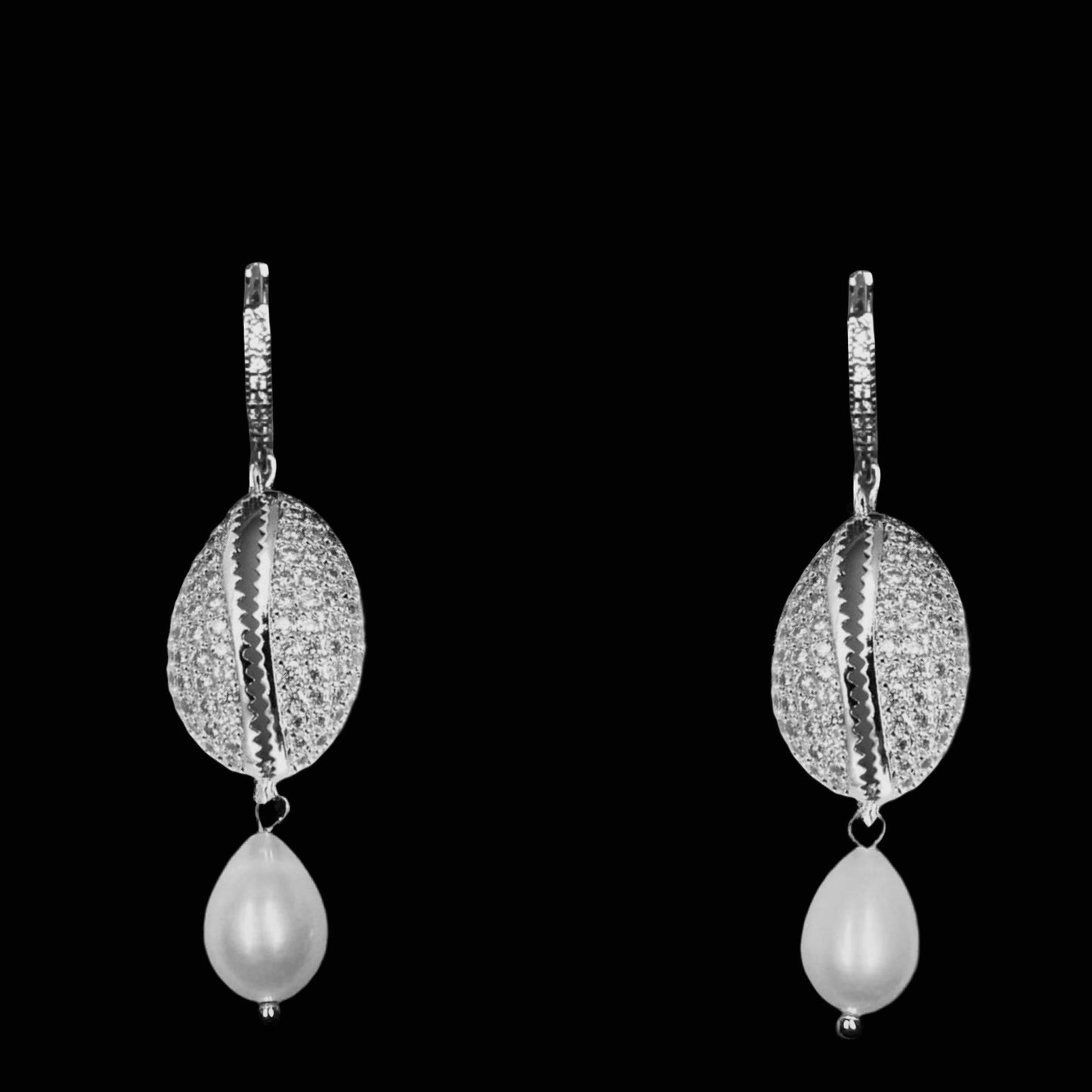 Pair of silver cowrie shell earrings with pearl drops on a black background