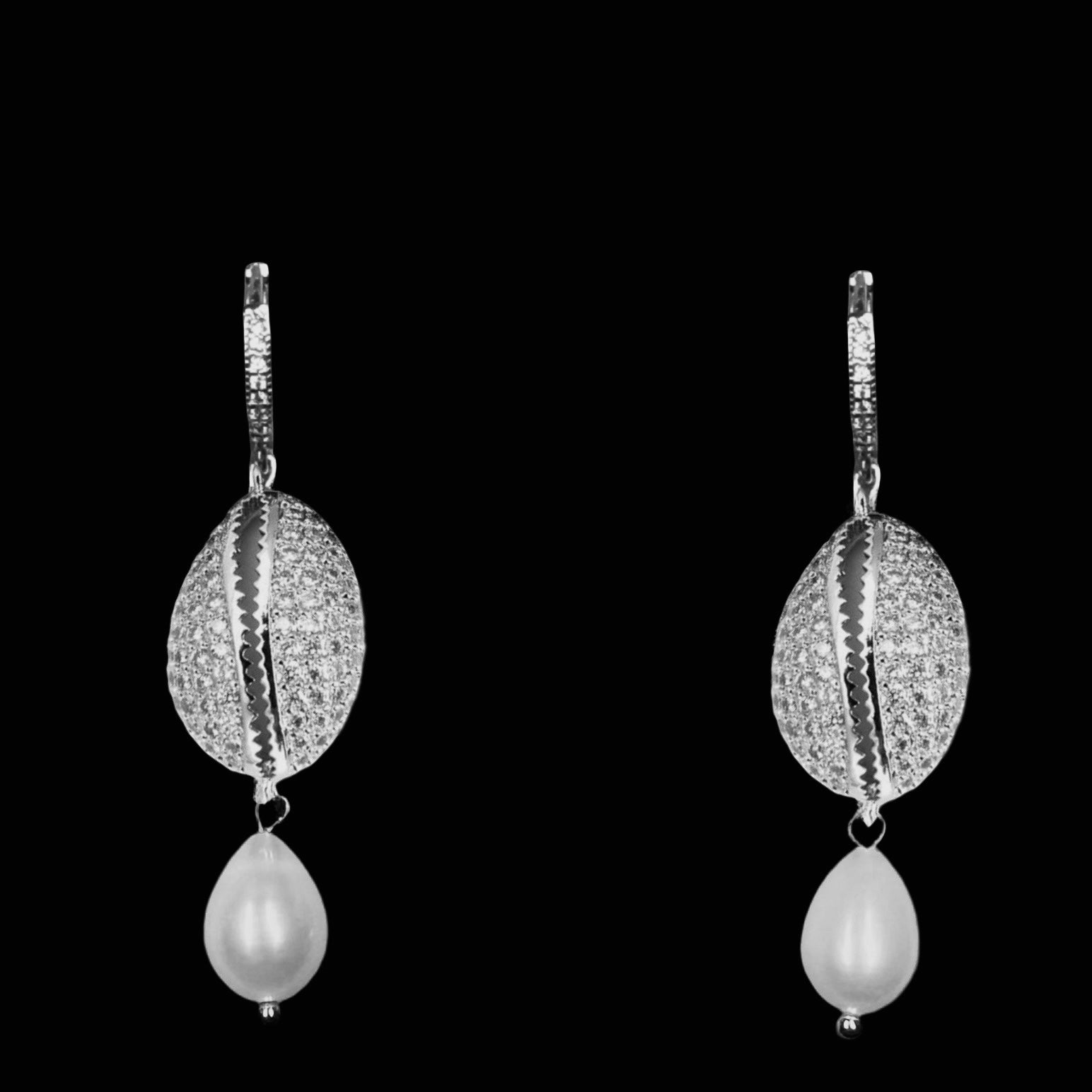 Pair of silver cowrie shell earrings with pearl drops on a black background