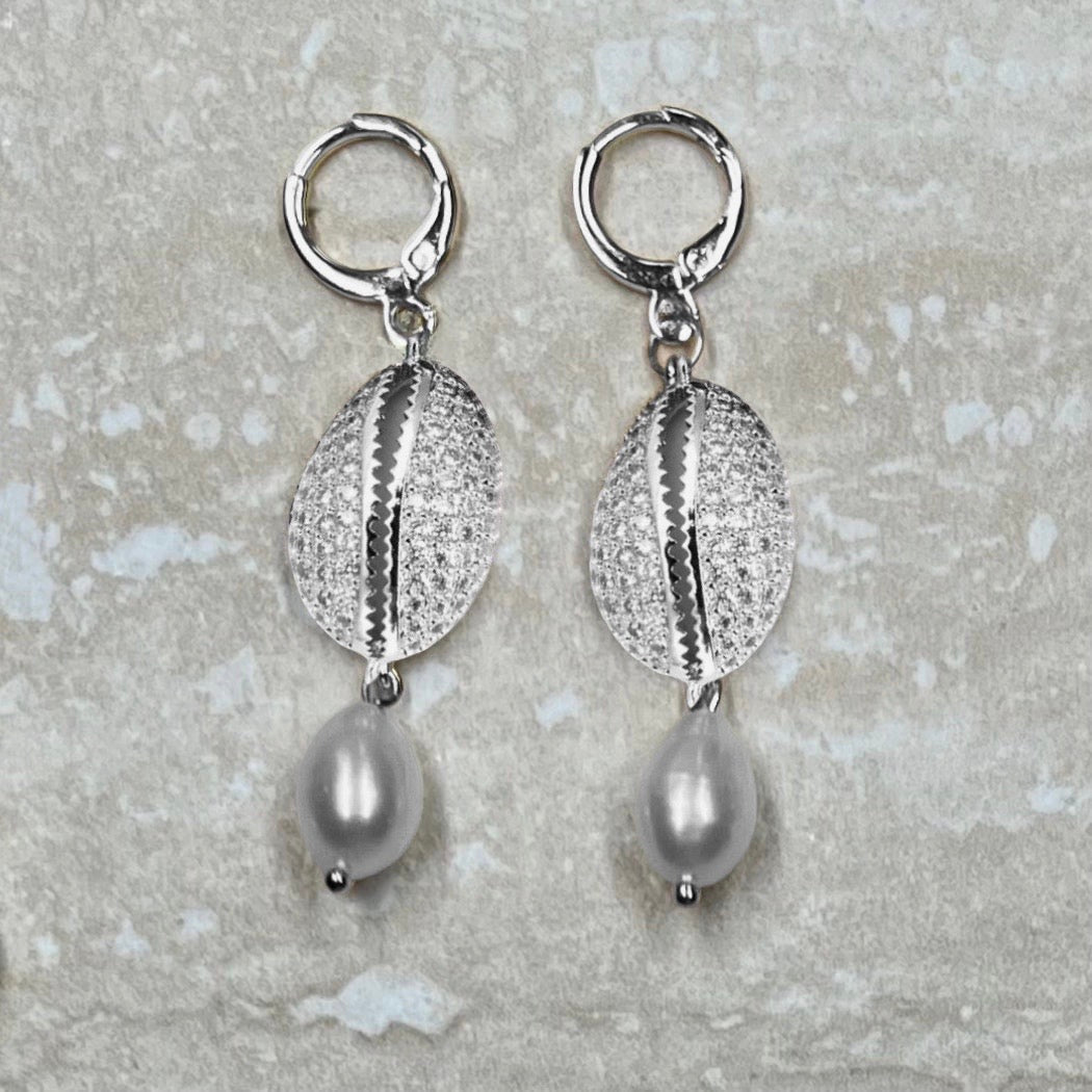 Silver CZ Cowrie Shell and freshwater teardrop pearl earrings On travertine background 